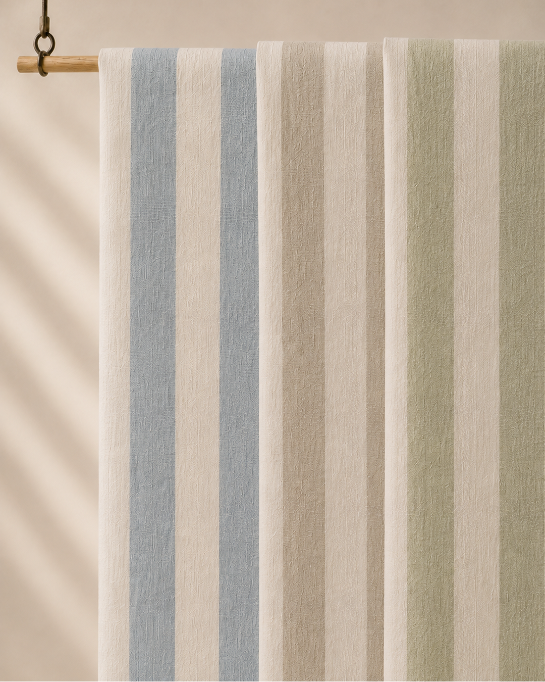 A striped fabric panel or curtain hanging from a wooden rod, featuring vertical stripes in light blue, cream, beige, and sage green against a warm beige background.